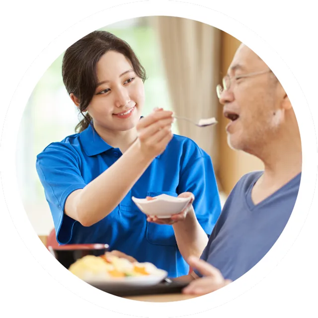 介護サービスのイメージ - 若い女性が高齢者に食事介助を行っている様子